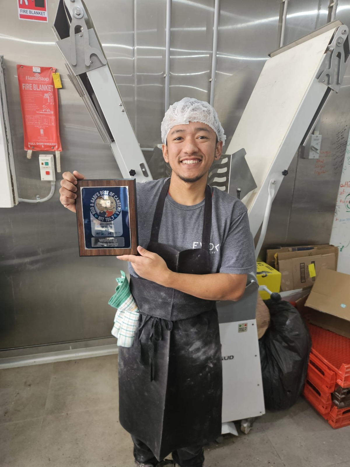 Evoke baker proudly holding the Canberra's Best Pie winner plaque